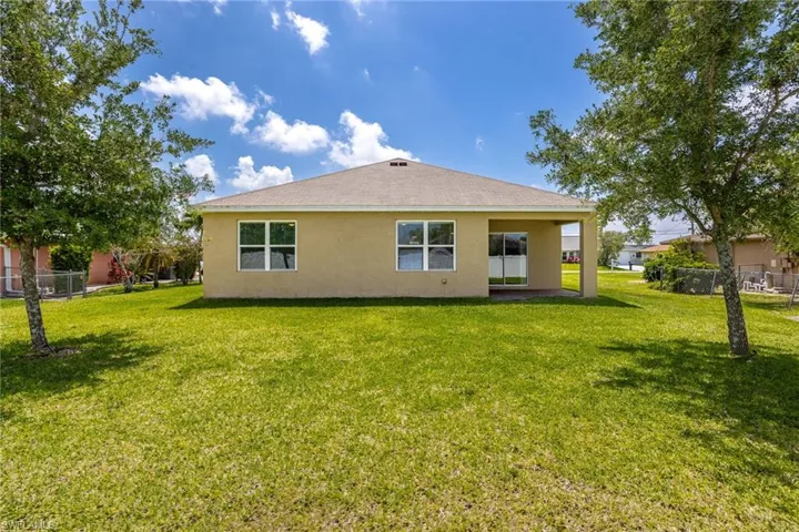 Back of property featuring a yard, stucco siding, and fence