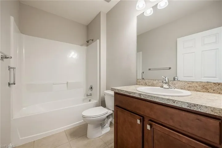Bathroom featuring vanity, toilet, tile patterned flooring, and shower / bathtub combination