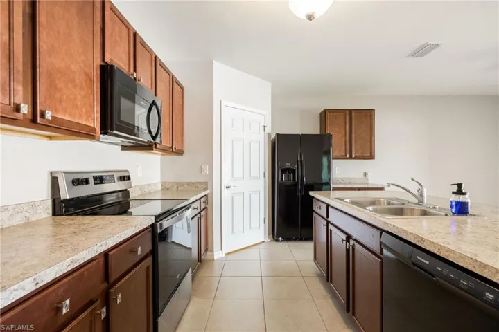 Kitchen with light countertops, visible vents, a sink, and black appliances