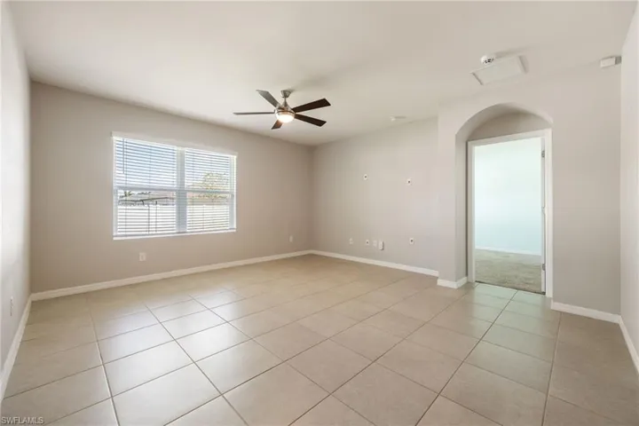 Unfurnished room with light tile patterned flooring, ceiling fan, and baseboards