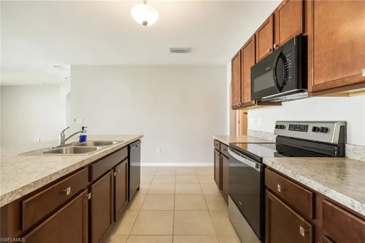 Kitchen with black microwave, visible vents, light countertops, a sink, and electric stove