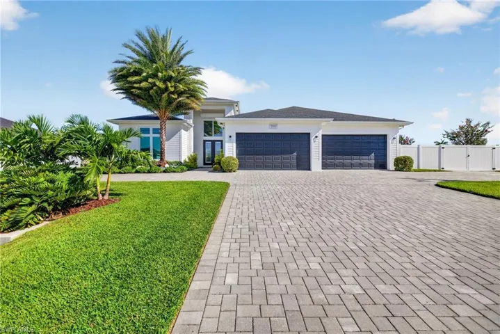 Front elevation with wide pavered circular drive and mature landscaping