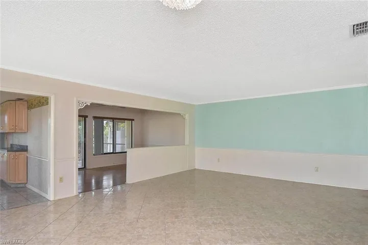 Spare room featuring ornamental molding, a textured ceiling, and light tile patterned floors
