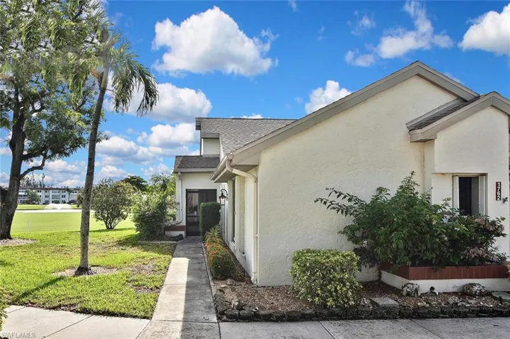 View of property exterior featuring stucco siding, a lawn, and a shingled roof