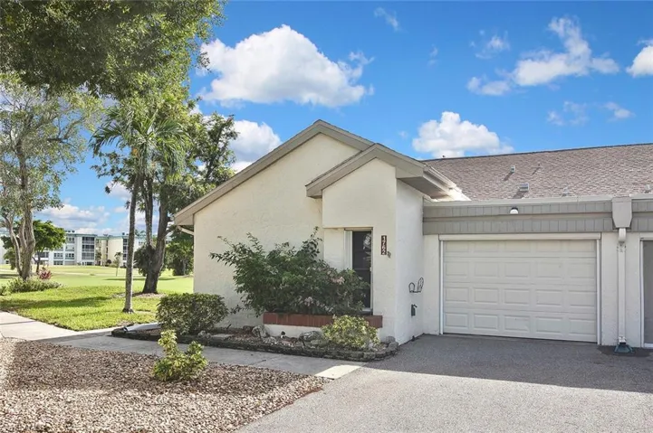 View of front of property with stucco siding, a front yard, an attached garage, and driveway