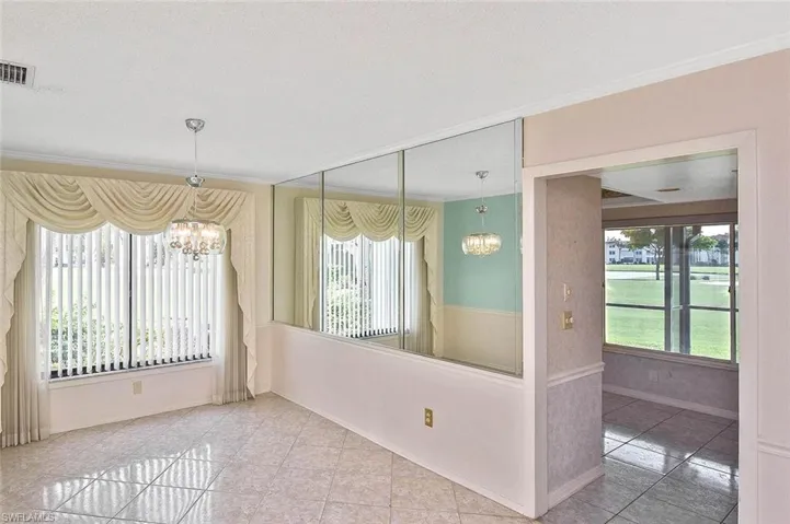 Empty room featuring a chandelier, tile patterned floors, and ornamental molding
