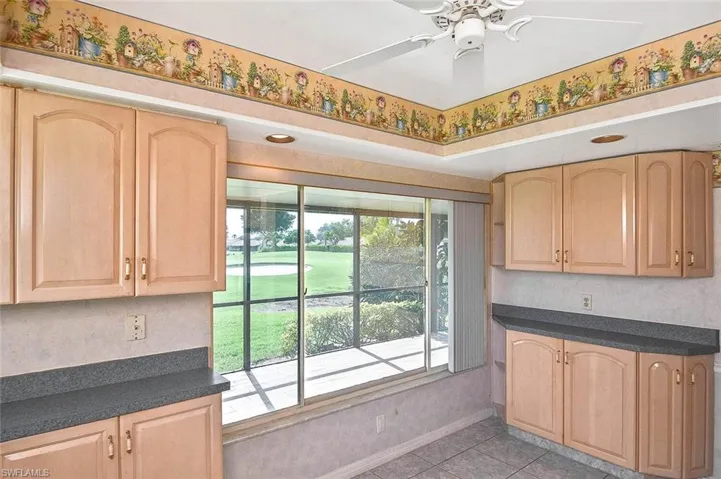 Kitchen featuring light brown cabinetry, light tile patterned flooring, dark countertops, and ceiling fan