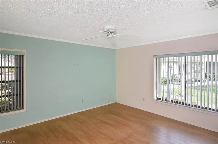 Spare room with wood finished floors, crown molding, a ceiling fan, and a textured ceiling
