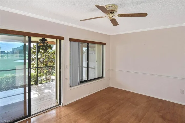 Empty room with a ceiling fan, plenty of natural light, crown molding, wood finished floors, and a textured ceiling
