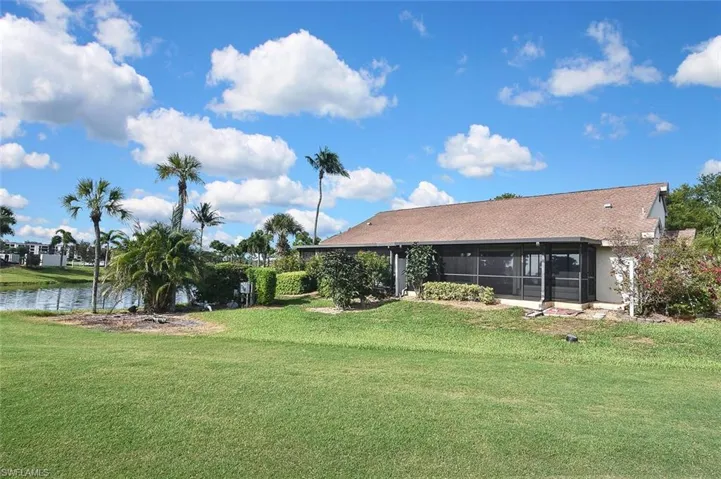 View of green lawn with a water view and a sunroom