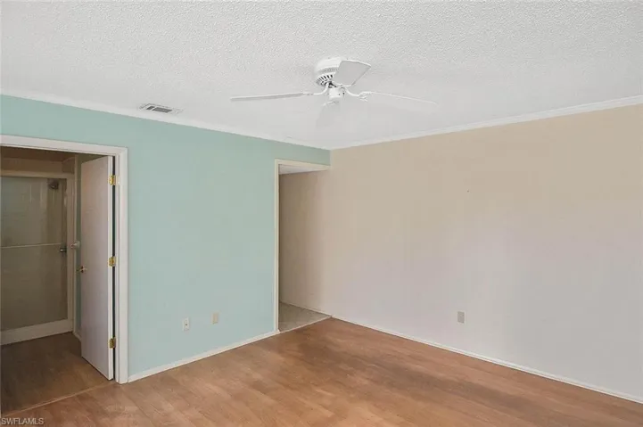 Unfurnished bedroom featuring wood finished floors, ornamental molding, a textured ceiling, ceiling fan, and a closet