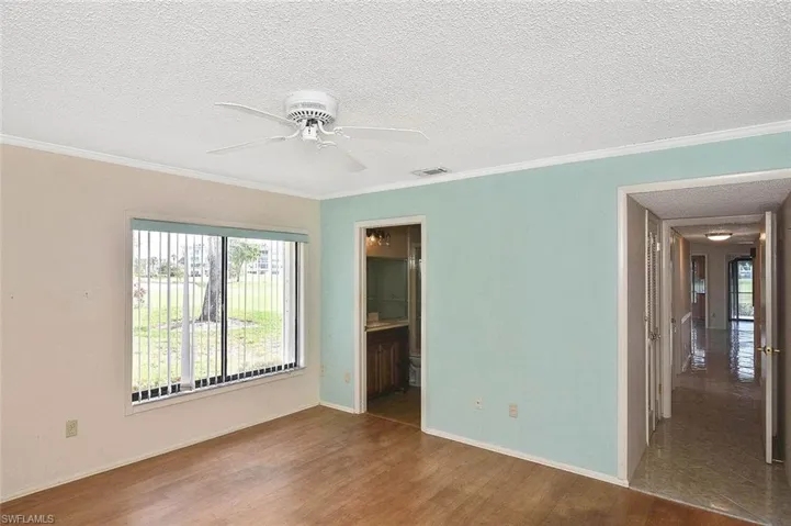 Empty room featuring wood finished floors, a ceiling fan, ornamental molding, and a textured ceiling