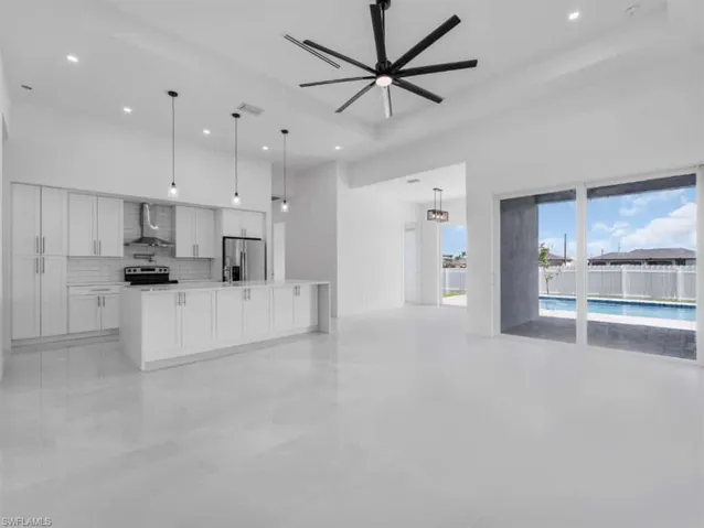 Kitchen with open floor plan, backsplash, white cabinetry, wall chimney exhaust hood, and stainless steel refrigerator with ice dispenser