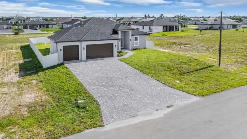 View of front of property featuring a residential view, a garage, stucco siding, decorative driveway, and roof with shingles