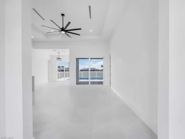 Hallway featuring a tray ceiling, recessed lighting, and tile patterned floors