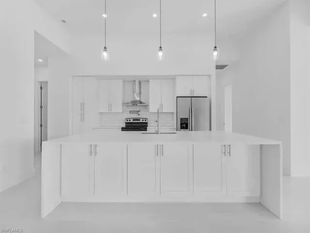 Kitchen with stainless steel fridge with ice dispenser, tasteful backsplash, wall chimney range hood, light countertops, and white cabinetry