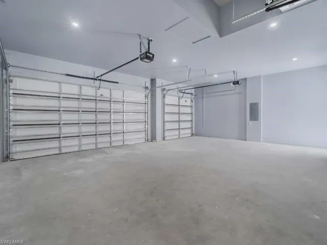 Garage featuring recessed lighting, a garage door opener, and electric panel