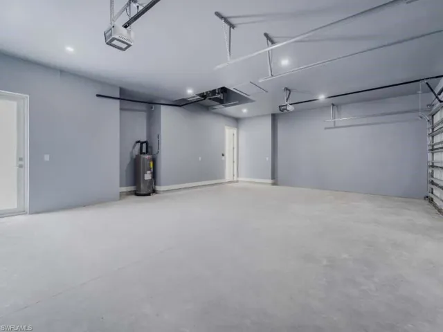 Garage with electric water heater, a garage door opener, and recessed lighting