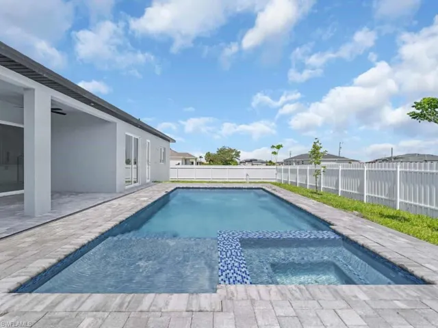View of swimming pool with a fenced backyard, a pool with connected hot tub, and a patio