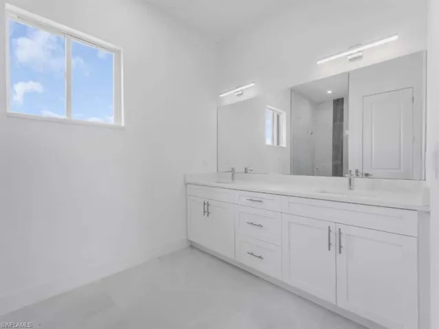 Full bath featuring a marble finish shower and double vanity