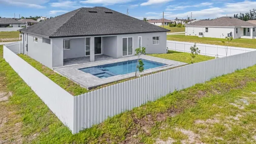 View of swimming pool with a fenced backyard, a residential view, and a pool with connected hot tub