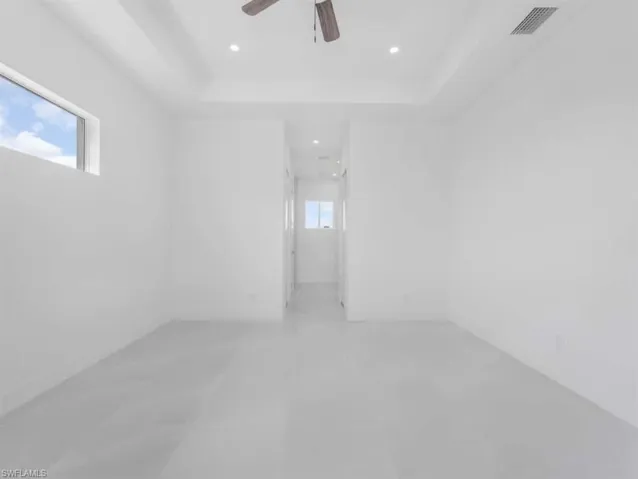 Unfurnished room with a ceiling fan, a raised ceiling, and recessed lighting
