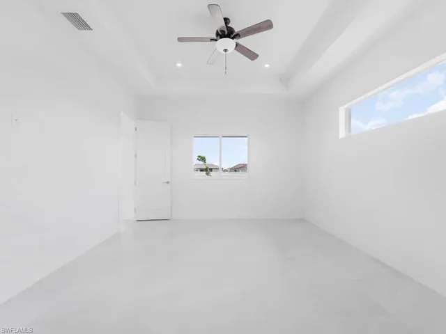 Spare room with a ceiling fan, a raised ceiling, and recessed lighting
