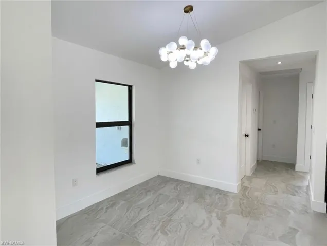 Unfurnished room with lofted ceiling and a chandelier