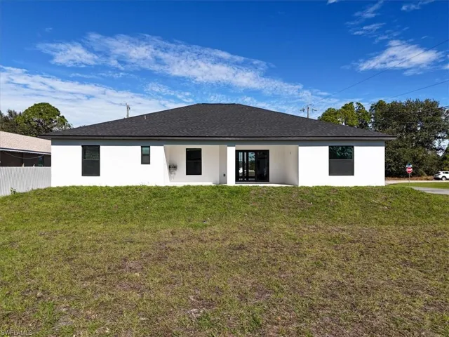 Back of property with stucco siding, a patio area, and a shingled roof