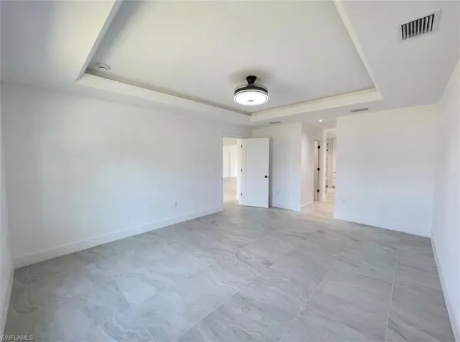 Unfurnished bedroom featuring baseboards and a tray ceiling
