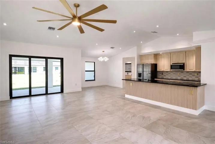 Kitchen featuring open floor plan, stainless steel appliances, vaulted ceiling, a ceiling fan, and a chandelier