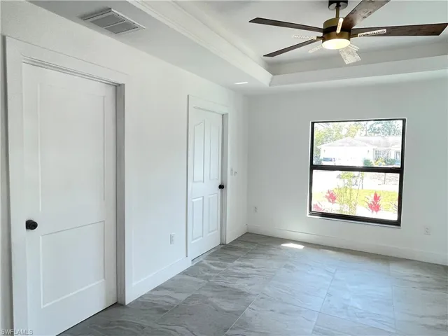 Unfurnished bedroom with a ceiling fan and a tray ceiling