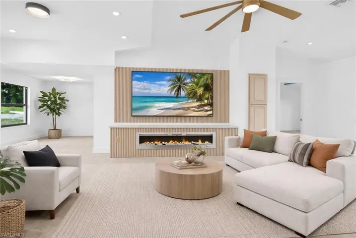Living room featuring recessed lighting, a glass covered fireplace, a ceiling fan, and light colored carpet