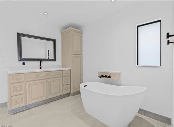 Full bath featuring vanity, a soaking tub, and recessed lighting