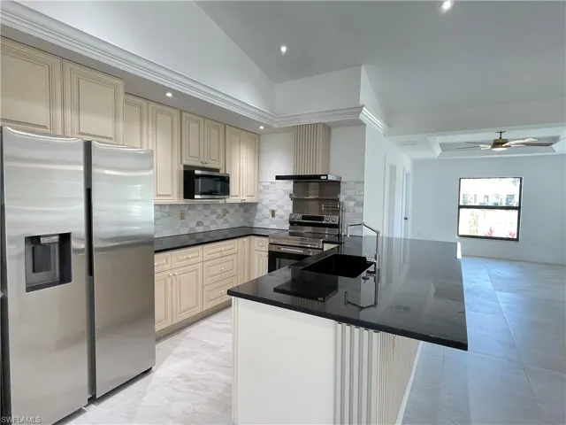 Kitchen with cream cabinets, stainless steel appliances, a peninsula, tasteful backsplash, and ceiling fan
