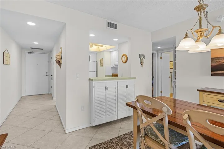 Dining area with a textured ceiling, visible vents, a chandelier, baseboards, and light tile patterned floors