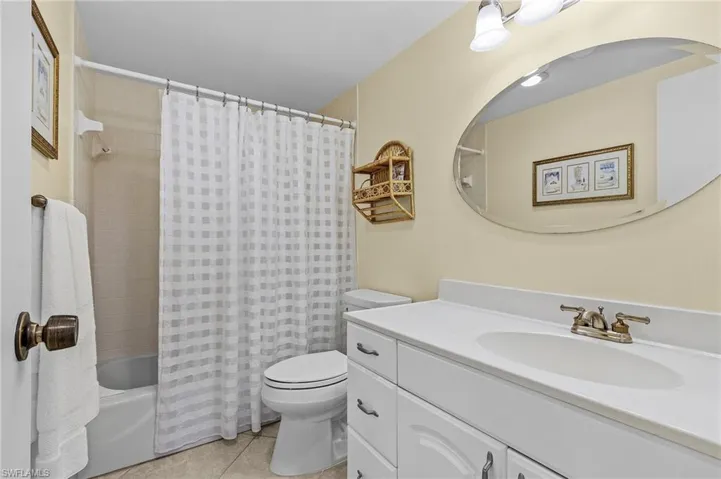 Bathroom featuring shower / bathtub combination with curtain, toilet, tile patterned flooring, and vanity