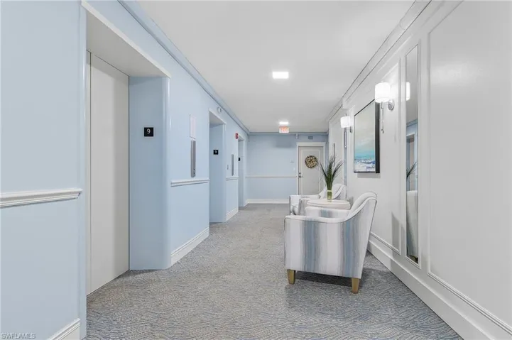 Hall featuring elevator, carpet flooring, and baseboards