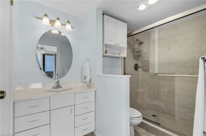 Full bath featuring a stall shower, toilet, ceiling fan, and vanity