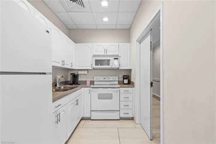 Kitchen featuring a sink, white cabinetry, white appliances, visible vents, and a paneled ceiling