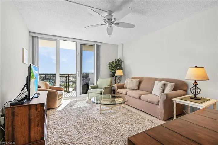 Living room with a textured ceiling, expansive windows, and ceiling fan