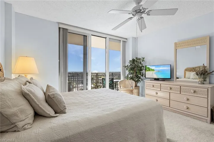 Bedroom featuring floor to ceiling windows, access to exterior, ceiling fan, and a textured ceiling
