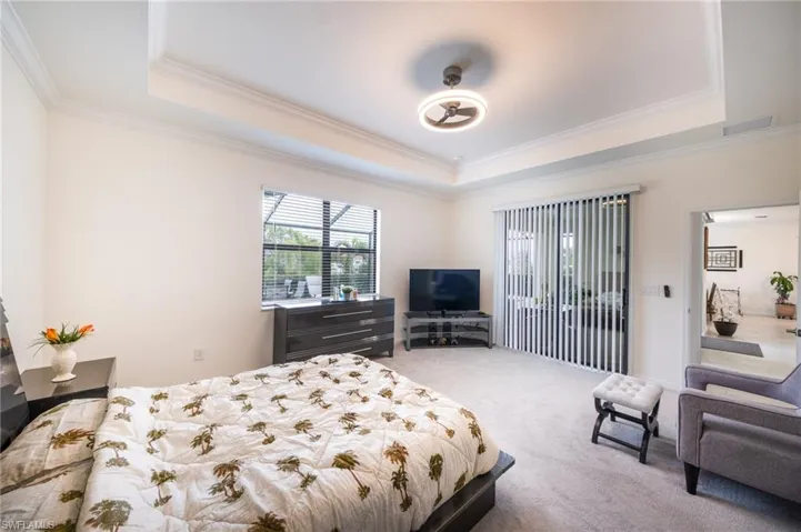 Carpeted bedroom with a raised tray ceiling and crown molding