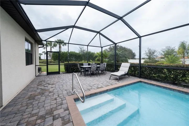 View of pool with an exterior dining area and screen enclosure
