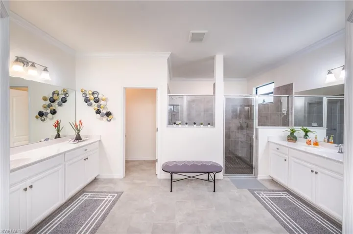 Master Bathroom featuring crown molding, walk in shower, and dual vanities