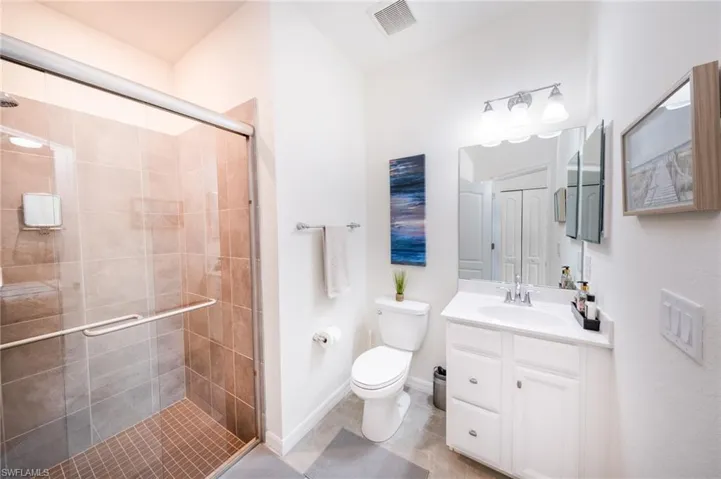 Guest En-Suite Bathroom featuring toilet, vanity, tile flooring, and a shower with shower door
