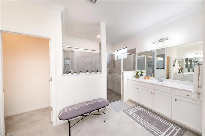 Master Bathroom featuring tile flooring, crown molding, walk in shower, private water closet, and dual vanities