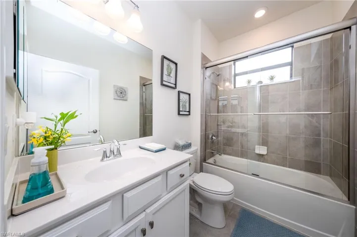 Full Main Guest bathroom featuring toilet, enclosed tub / shower combo, and vanity