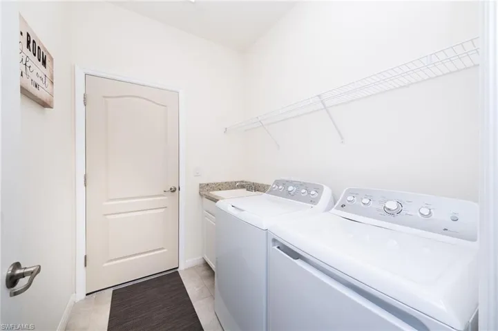 Laundry room with cabinets, washing machine and clothes dryer, and light tile floors