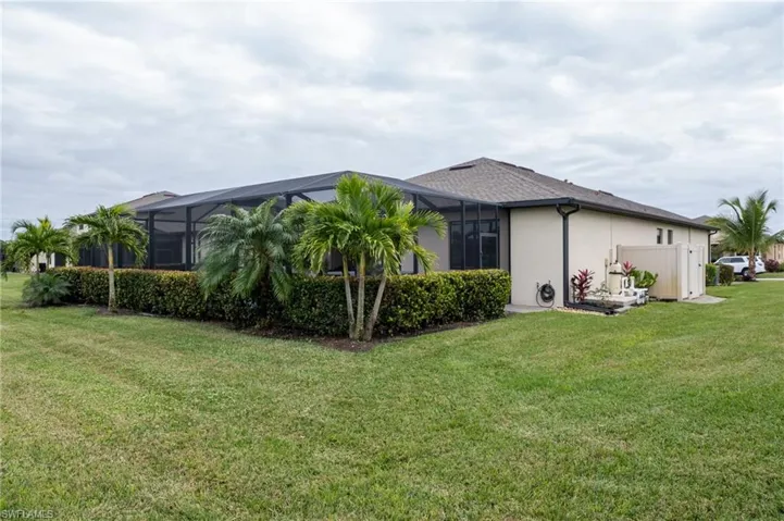 View of property exterior with a large pool enclosure with landscaping for privacy